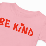 Pink t-shirt with 'BE KIND' text in red on a white background