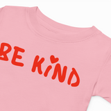 Pink t-shirt with 'BE KIND' text in red on a white background