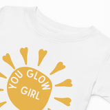 White sweatshirt with yellow sun graphic and 'You Glow Girl' text on a white background