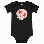 A black short-sleeve baby bodysuit with a graphic of a light pink skull on the chest, featuring a red heart, a red X, and a red dot, displayed on a clean white background.