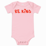Pink baby short-sleeve one-piece bodysuit with red hand-lettered "Be Kind" graphic and small heart above the "i" on the front.