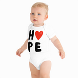 Baby wearing a white onesie with 'HOPE' and a heart design on a white background