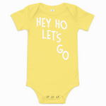 Yellow baby onesie with 'HEY HO LET'S GO' text on a white background