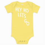 Yellow baby onesie with 'HEY HO LET'S GO' text on a white background