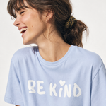 Woman wearing a light blue t-shirt with 'BE KIND' printed on it against a plain background