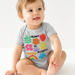 Smiling baby sitting in a heather gray "Bloom in Diversity" bodysuit featuring colorful flower, leaf, and rainbow graphics, against a white background.