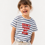 A young girl with brown hair wearing a white short-sleeve t-shirt with navy blue horizontal stripes and bold red text that reads 'DON'T YUCK MY YUM'. She is also wearing light beige shorts, set against a plain white studio background.