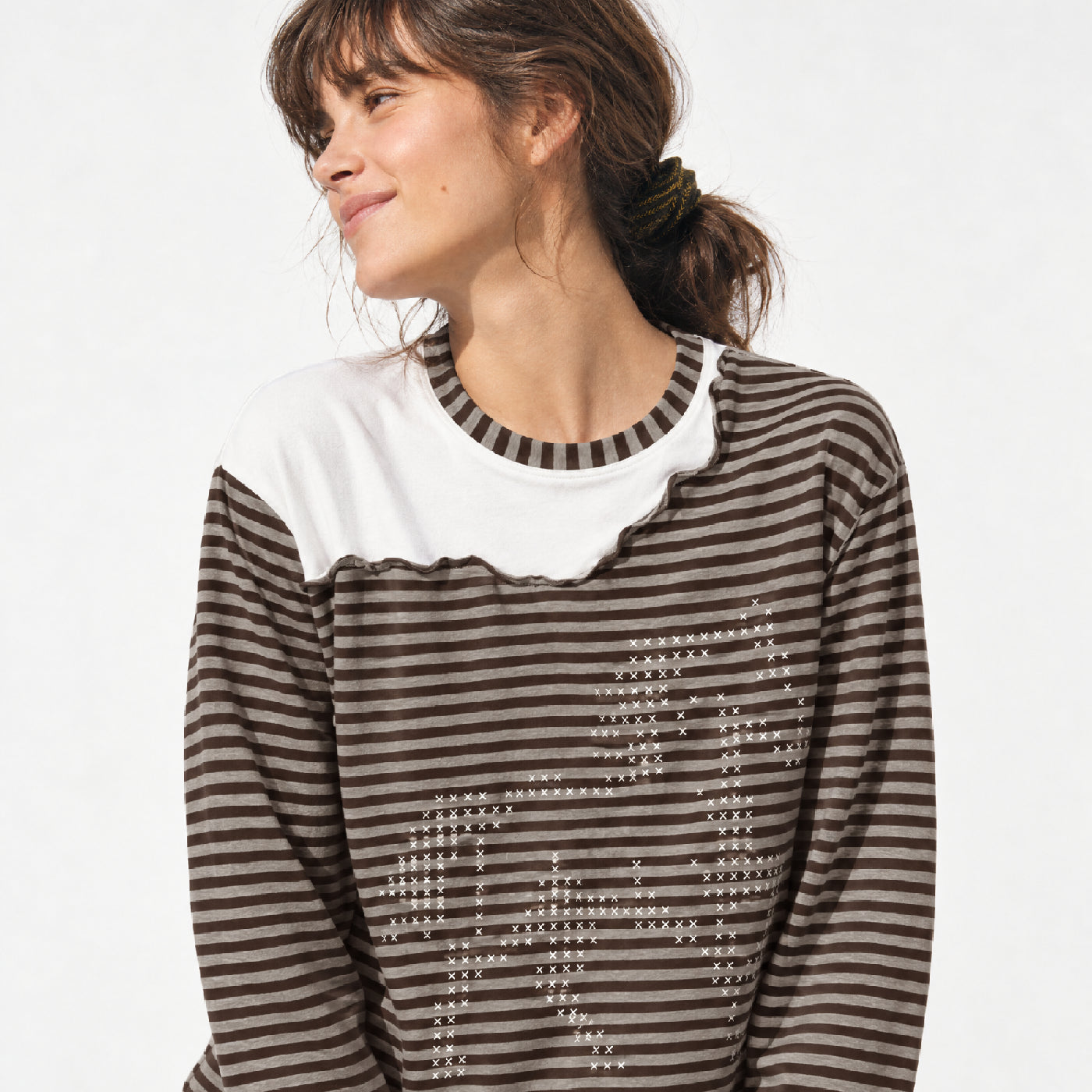 Woman with dark hair wearing a dark brown striped sweater with white collar detail.