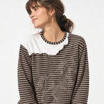 Woman with dark hair wearing a dark brown striped sweater with white collar detail.