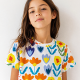 Young girl wearing a colorful floral-patterned shirt against a white background