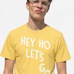 Person wearing a yellow t-shirt with 'HEY HO LET'S GO' text on a plain background
