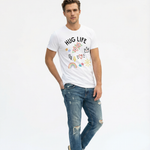 Man wearing a white t-shirt with 'HUG LIFE' text and colorful graphics, paired with ripped jeans on a light gray background.