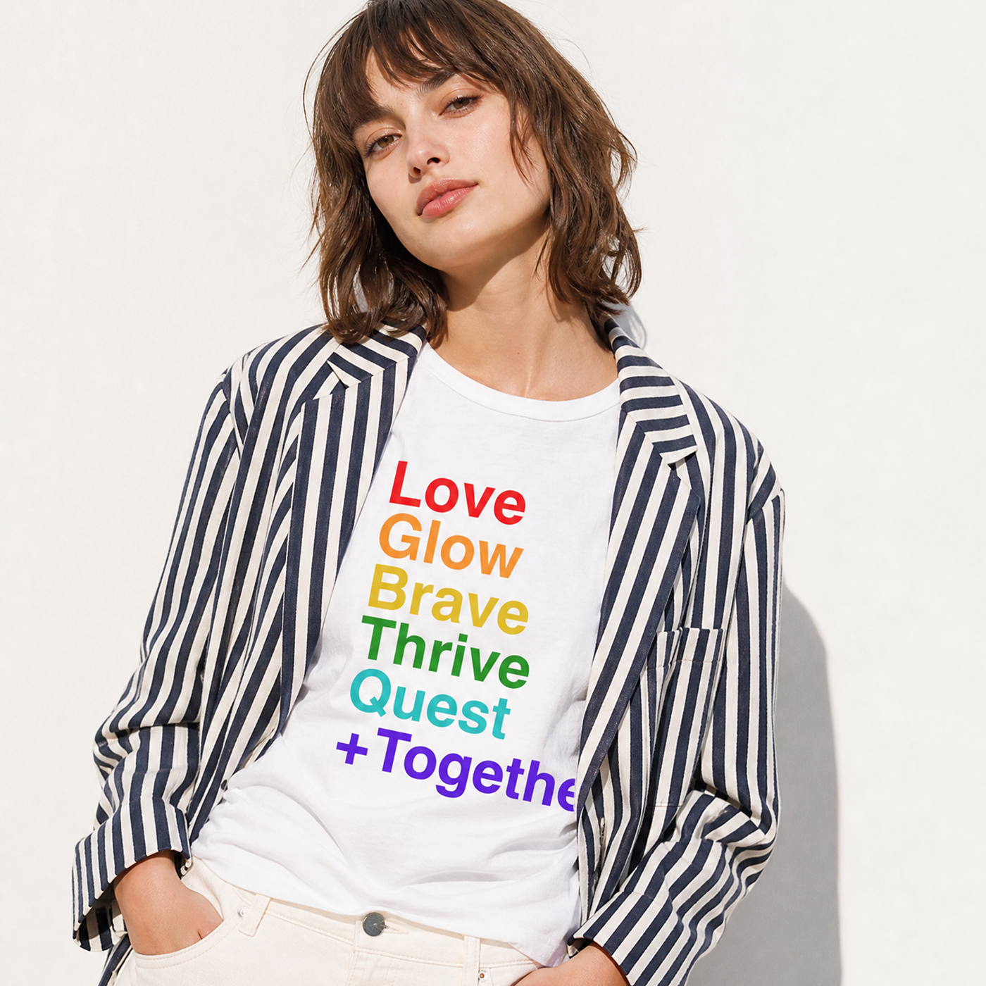 Person wearing a white t-shirt with colorful text and a striped jacket on a light background