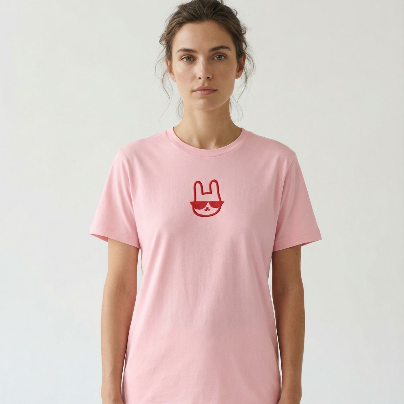 Person wearing a pink t-shirt with a red logo on a plain background