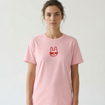 Person wearing a pink t-shirt with a red logo on a plain background