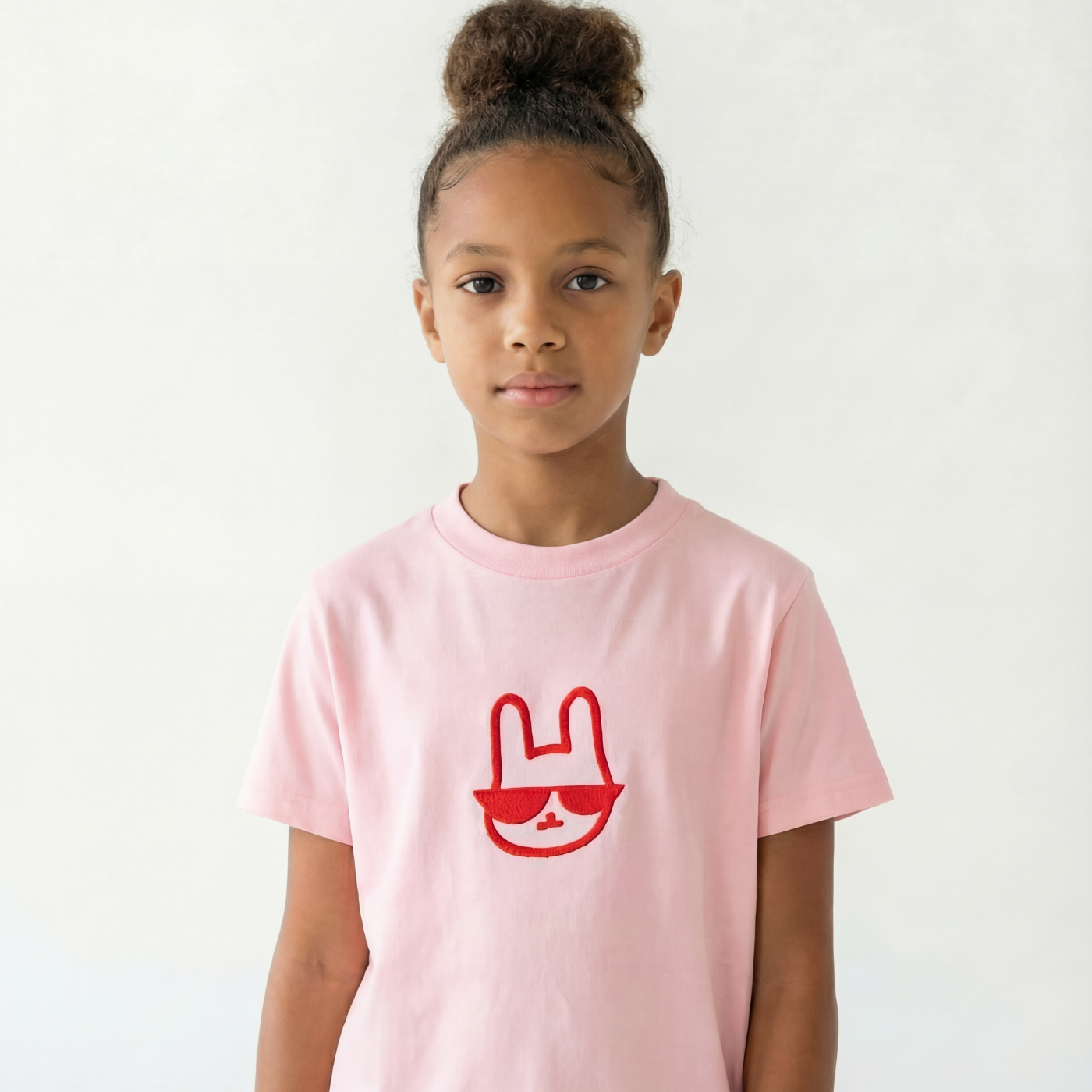 Child wearing a pink t-shirt with a red graphic on a white background