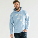Man wearing a light blue hoodie with 'HEY HO LET'S GO' text on a white background