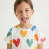 Child wearing a white t-shirt with colorful heart patterns on a plain background