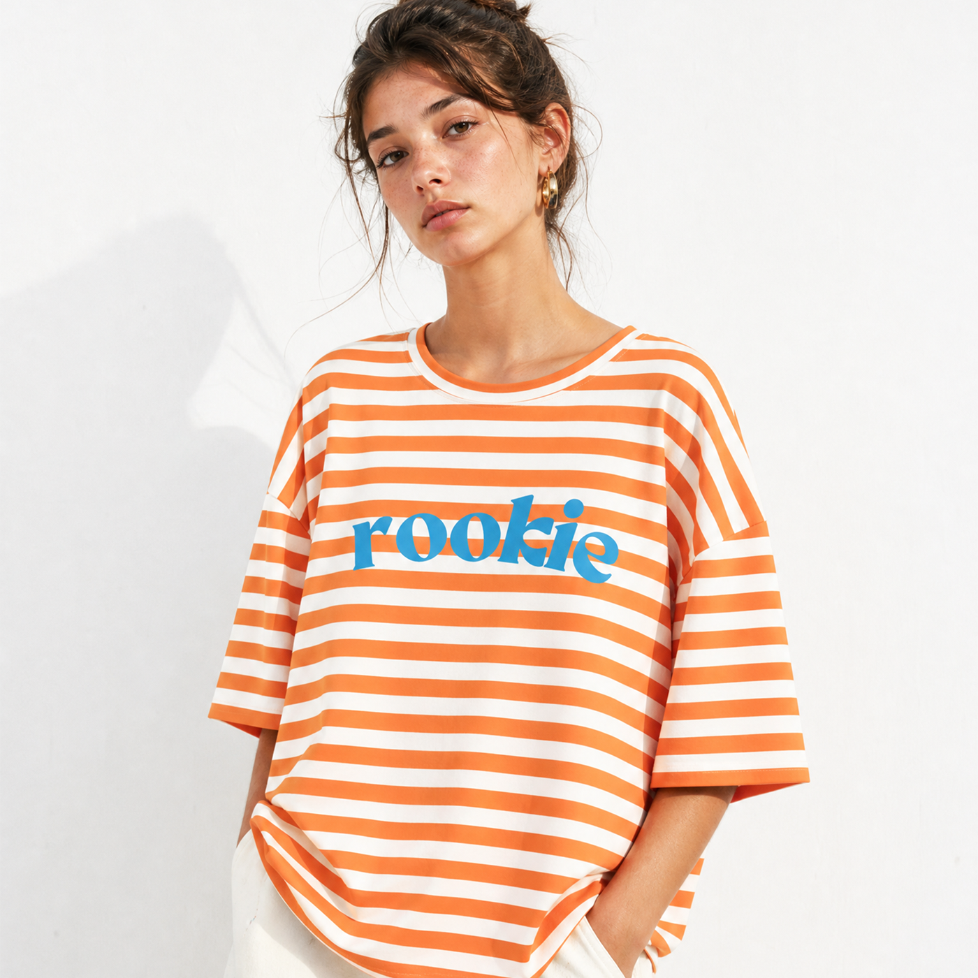 Woman wearing an orange and white striped shirt with 'rookie' text on a white background