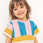 A young child wearing a short-sleeve crewneck t-shirt with vertical and horizontal color-blocked stripes in blue, pink, yellow, and cream, photographed against a clean white background.