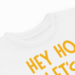 White t-shirt with yellow text 'HEY HO LET'S GO' on a white background