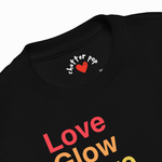 Close-up of a black t-shirt showing the inner neck label with 'chatter pop' and a red heart, and the lower front graphic reading 'Love Glow' in red and yellow gradient text.