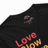 Close-up of a black short-sleeve t-shirt with a colorful graphic print reading 'Love glow' in red, orange, and yellow gradient text. The inner collar label shows the brand 'clother pop'.