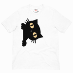 A white short-sleeve crewneck t-shirt featuring a graphic print of a black cat peeking out from behind with large beige eyes, shown against a plain white background.