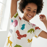 Child wearing a white t-shirt with colorful animal prints, smiling.